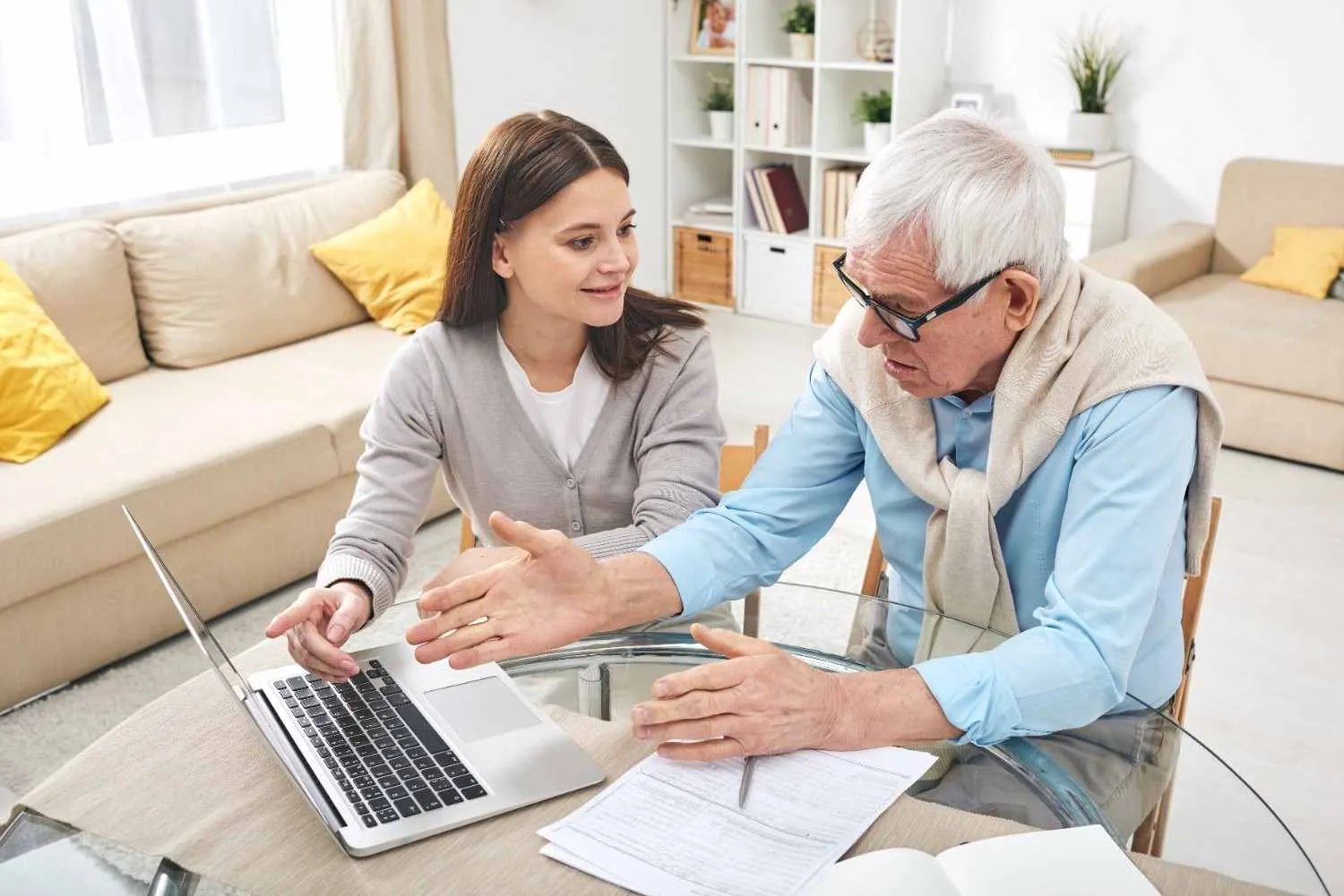 A woman and an older man going through paperwork beside a laptop at home